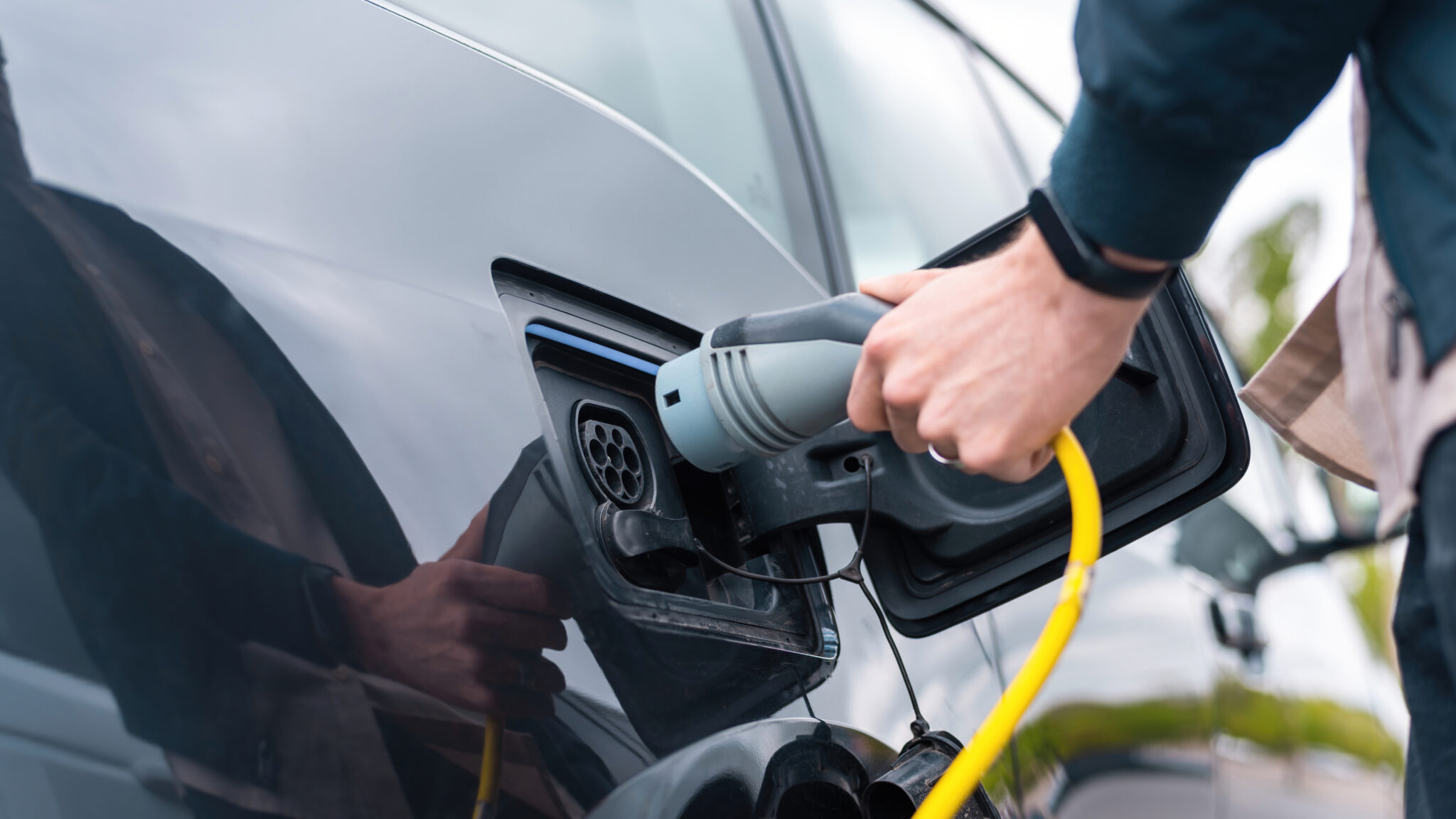 Driver plugging in an electric car charged by rooftop solar power