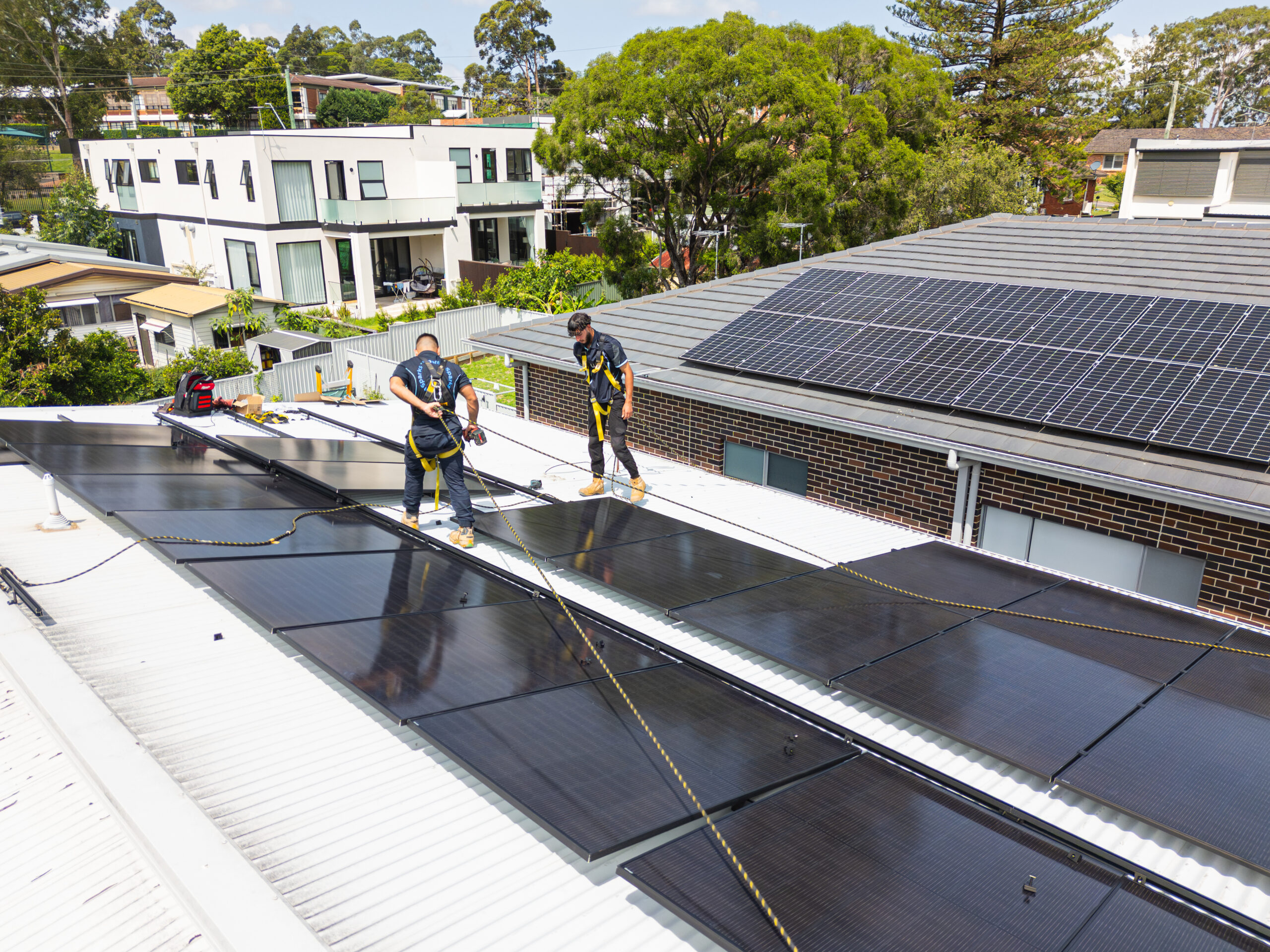 Two solar installers working on roof panels in Sydney.
