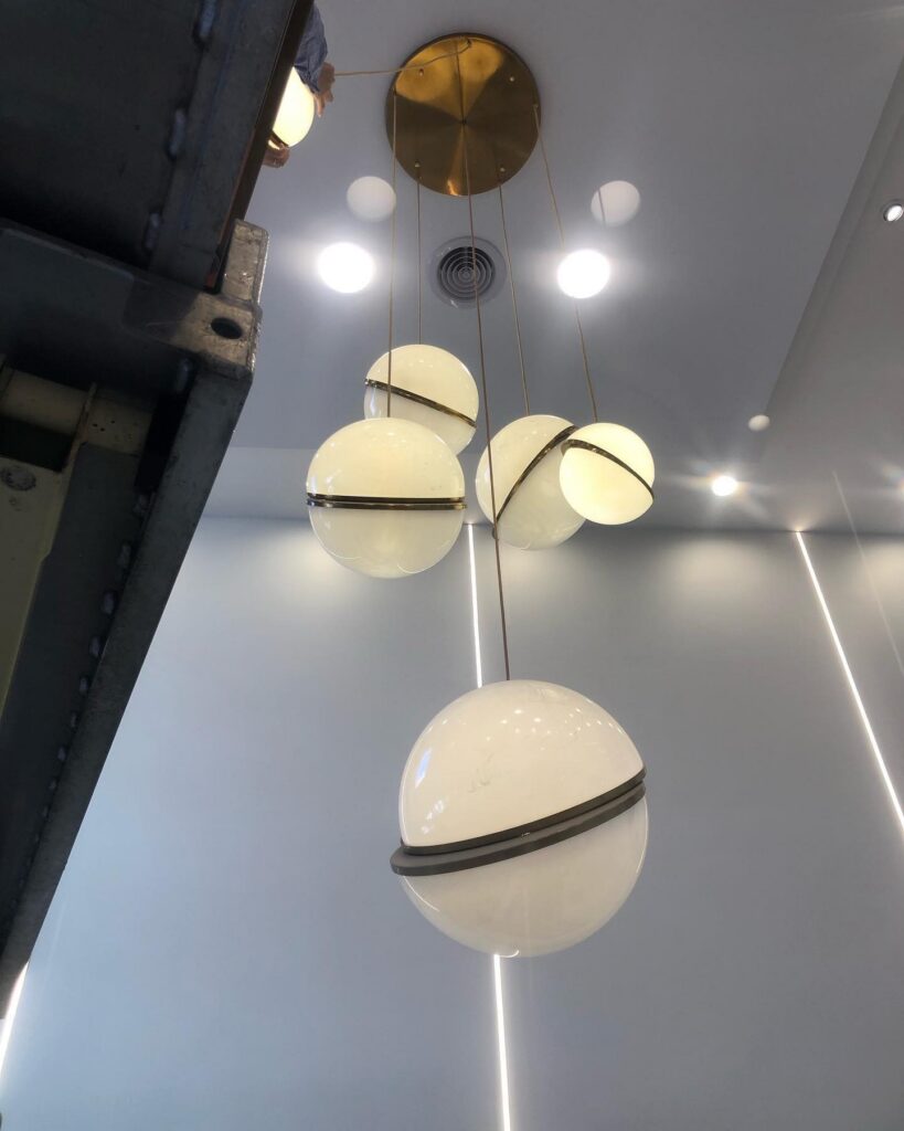Modern pendant light fixture with spherical shades and recessed downlights on a ceiling