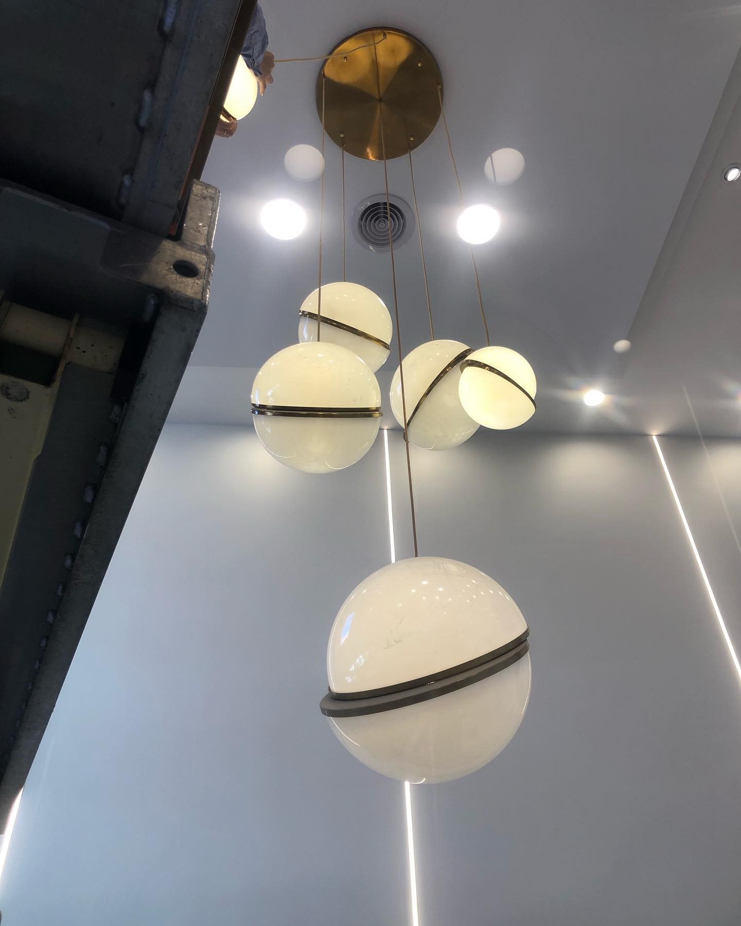 Modern pendant light fixture with spherical shades and recessed downlights on a ceiling